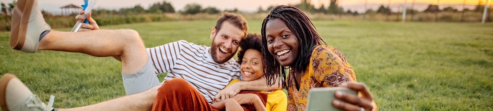 Parents and child taking a selfie outdoors.